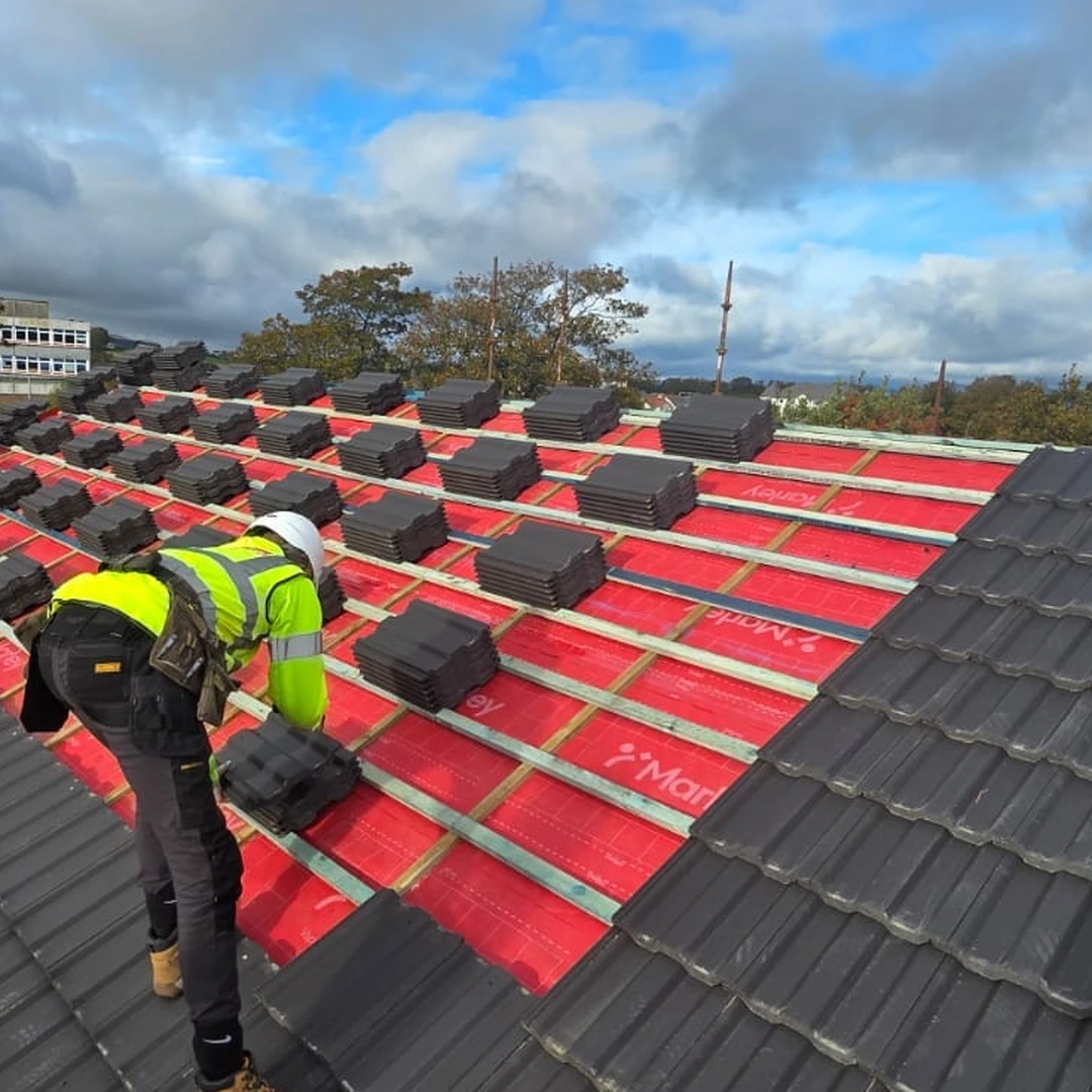 NuGen Exteriors roofer laying tiles over new underlay on a Lanarkshire re-roof